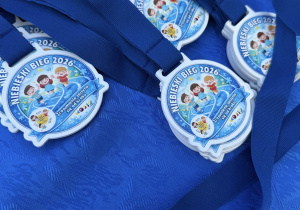 niebieskie medale z hasłem wydarzenia oraz logo przedszkola i MOSIR Łódź, które dzieci otrzymały po biegi