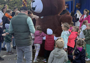 Dzieci bawią się w dużym misiem pluszowym.
