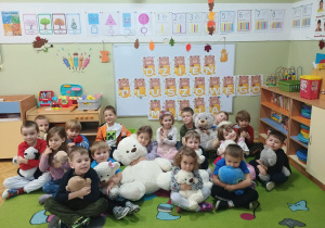 Dzieci pozują do zdjęcia grupowego na tle napisu "Dzień Misia"
