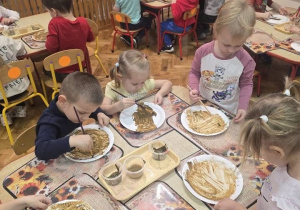 dzieci z grupy maluchów malują głowę misia na talerzyku papierowym