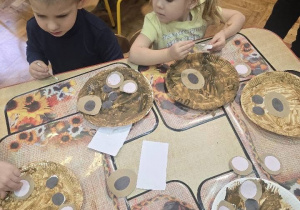dzieci z grupy maluchów malują głowę misia na talerzyku papierowym
