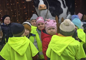 Dzieci w żółtych kamizelkach odblaskowych pozują z ze sztuczną krową