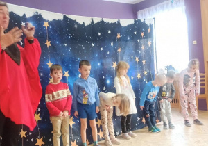 magik w czerwonym stroju i grupka dzieci wykonują sztuczkę, dzieci się kłaniają