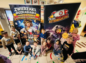 Dzieci pozują na tle dwóch plakatów Polskiego Planetarium Astronomicznego