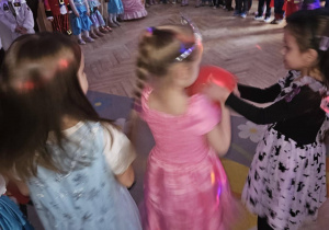 Dzieci stoją w okręgu i podają sobie czerwony balonik