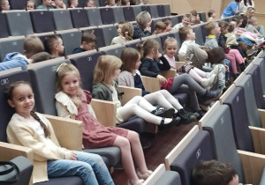 Dzieci siedzą na scenie Szkoły Muzycznej