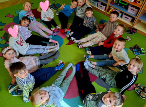 Dzieci siedzą w kole z wyciągniętymi prostymi nogami , na stopach mają kolorowe skarpetki