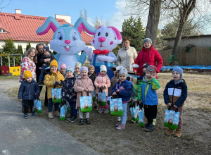 Dzieci pozują w ogrodzie do zdjęcia grupowego wraz z dwoma dużymi królikami