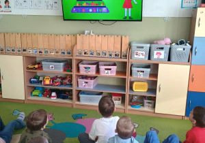 Dzieci oglądają na telewizorze film edukacyjny o zdrowym odżywianiu