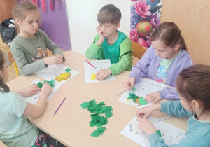 Dzieci wykonują pracę plastyczną z użyciem bibuły.
