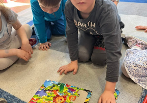 Chłopiec ma założone okulary na których jest folia i próbuje ułożyć puzzle