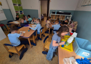 dzieci siedzą przy stolikach i tworzą swoje gniotki z baloników i mąki
