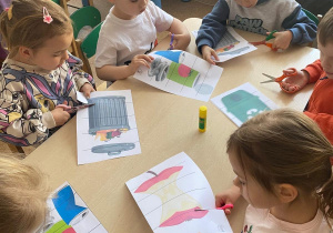 Dzieci siedzą przy stolikach i wycinają różne rodzaje śmieci z papieru