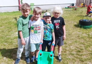 Czterech chłopców pozuje do zdjęcia grupowego w ogrodzie przedszkolnym.