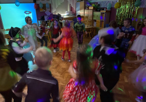 Grupa dzieci tańczy przy muzyce przy świetle dyskotekowym