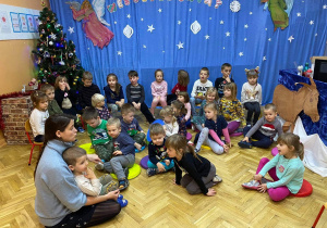 Dzieci siędzą na pufach rozmawiają z wychowawcą na temat świąt