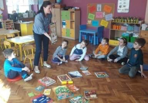 Dzieci oglądają książki wspólnie z nauczycielem.