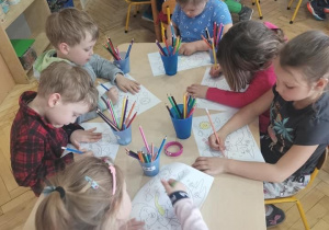 Przedszkolaki przy stolikach kolorują kolorowankę o planecie Ziemia