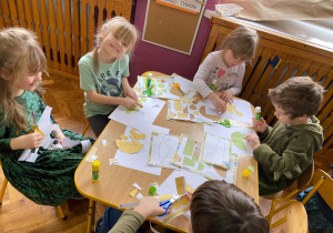 Praca plastyczna - dzieci układają dinozaury z figur geometrycznych.