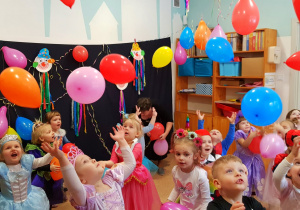 Dzieci z grupy najmłodszej bawią się balonami podczas balu karnawałowego.