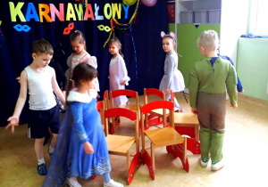 Dzieci z najstarszej grupy biorą udział w konkursie "Gorące krzesełko" Dzieci ustawione w kole, chodzą wokół ustawnionych w kole krzeseł.