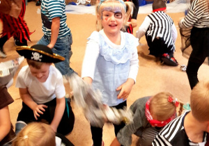 Dzieci podczas zabawy "bitwa na morzu". Dziewczynka na pierwszym planie rzuca w stronę obiektywu gazetową kulą armatnią.