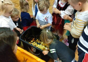 Dzieci wyjmują czekoladowe monety ze skrzyni skarbów.