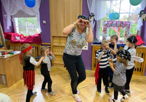 Dzieci z nauczycielką tańczą i bawią się podczas balu.