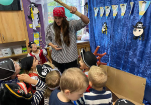 Nauczycielka i dzieci przebrani w stroje piratów bawią się podczas balu.
