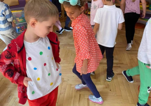 Dzieci w strojach w kropki tańczą wokół okrągłych obręczy.