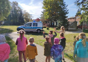 Dzieci obserwują samochód policyjny.