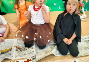 Dziewczynki skończyły malować listki pędzlami trzymanymi w ustach.