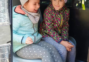 Dwie dziewczynki siedzą wewnątrz radiowozu.