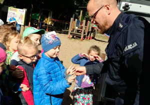 Policjant pokazuje dzieciom kajdanki.
