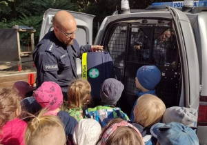 Policjant demonstruje dzieciom wnętrze radiowozu tzw. więźniarki.
