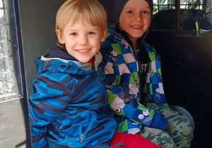 Dwóch chłopców siedzi wewnątrz radiowozu.