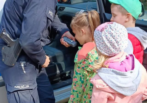 Dzieci przestawiają sie do policyjnego megafonu.