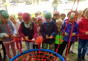 Dzieci ustawione wokół huśtawki rozcinają czerwoną wstęgę.