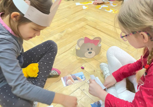 Dwie dziewczynki układają puzzle z wizerunkiem misia.