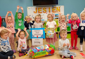 Zdjęcie grupowe Jagódek - najmłodszych przedszkolaków. Dzieci prezentują zdobyte w konkursie nagrody.