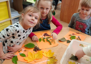 Dziewczynki siedzą przy stoliku, tworzą swoje kartki do zielnika.