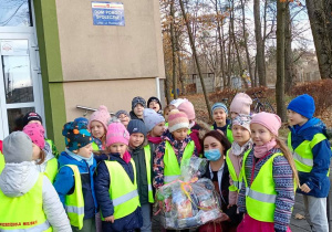 Dzieci pozują do zdjęcia z panią odbierającą paczkę od dzieci przed budynkiem DPS przy ul. Rudzkiej. Z uwagi na COVID dzieci nie mogły spotkać się osobiście z seniorami.