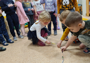 Dzieci układają na podłodze "węża z kredek" poprzed dokładanie kolejnej kredki do poprzedniej.