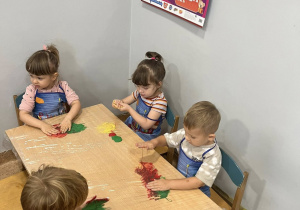 Dzieci mieszają farby dłońmi.