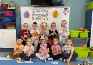 Dzieci pozują do zdjęcia na tle napisu "Dzień Przedszkolaka"