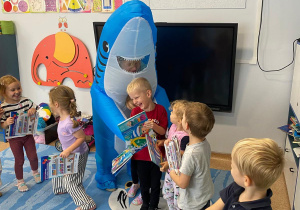 Dzieci przytulają się do nauczycielki przebranej za rekina.