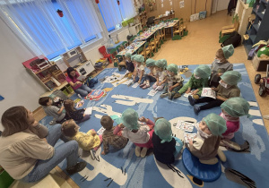 Dzieci siedzą w kręgu na dywanie.