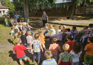 Dzieci bawią się w przeciąganie liny w ogrodzie przedszkolnym.