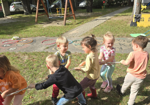 Dzieci bawią się w przeciąganie liny w ogrodzie przedszkolnym.