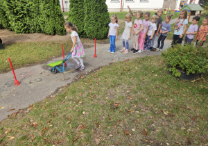 Dzieci prowadzą taczkę przez przeszkody.